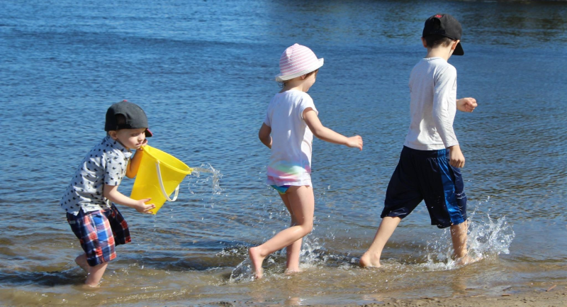 kids walking a shoreline with beach buckets