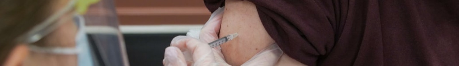 Nurse giving a COVID-19 vaccine to man