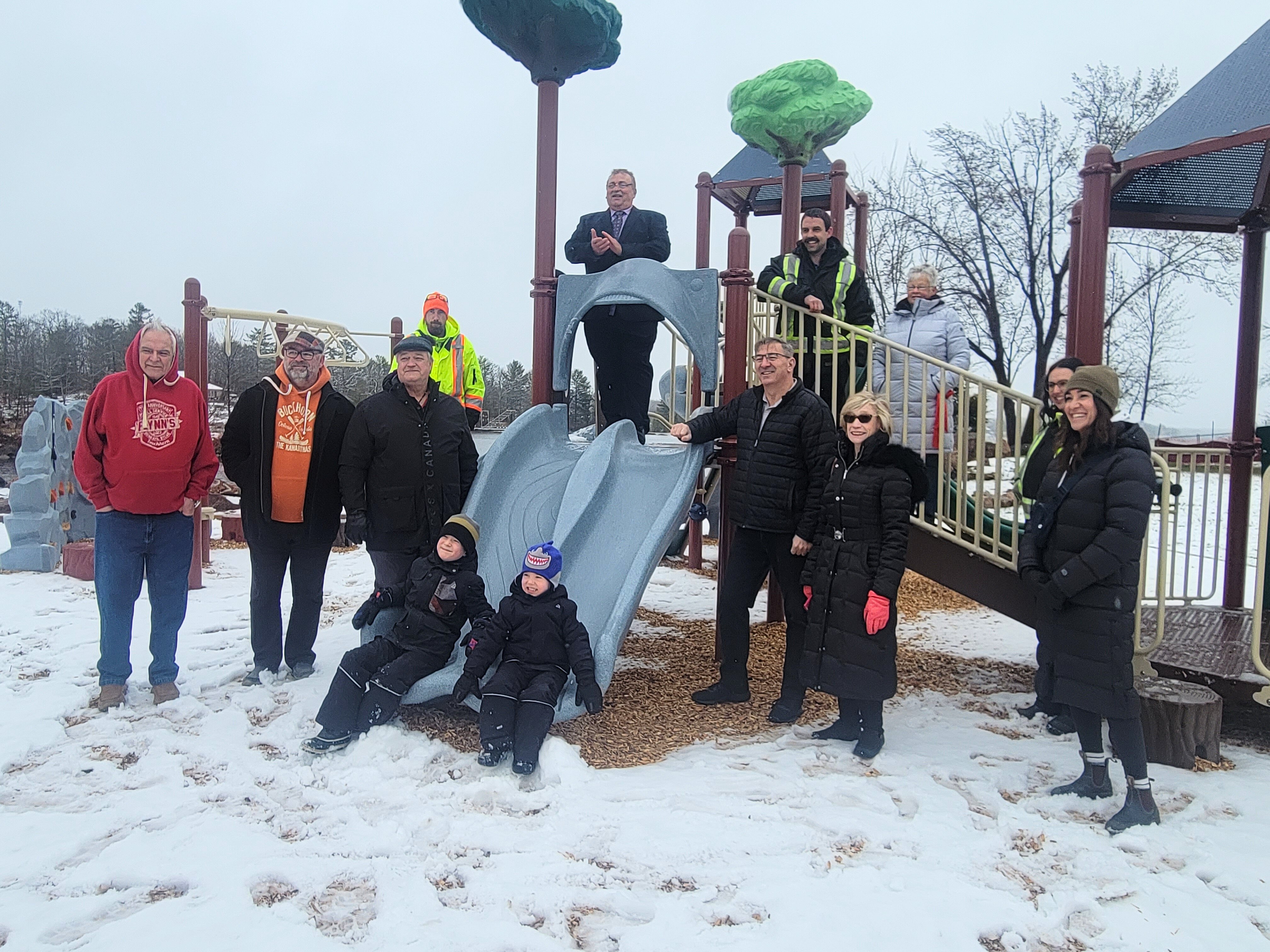 Members of the public and Municipal staff gather around playground for a photo.