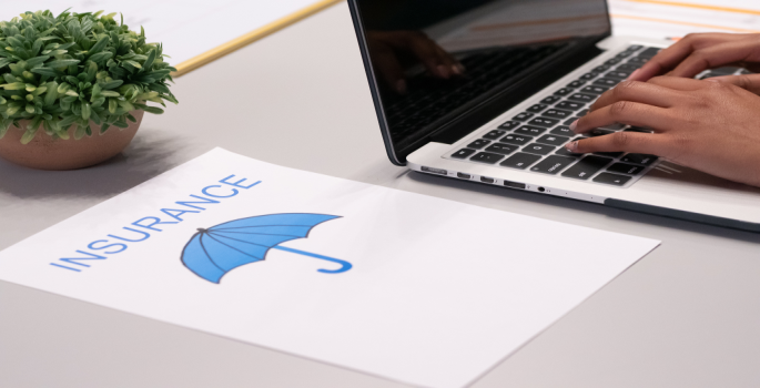 graphic of an umbrella with words Insurance beside a laptop